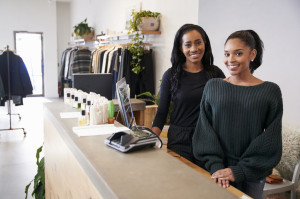 Two women smiling behind the counter in clothing store