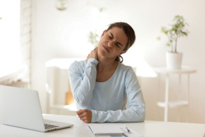 Young female suffers from neck ache at workplace