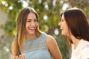 38251078 - happy women talking and laughing in a park with a green background